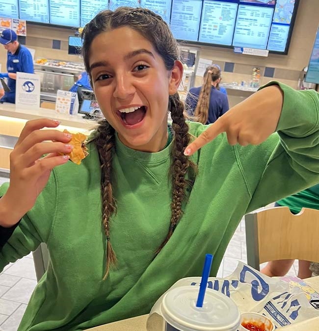 Girl points to her ButterBurger and smiles.