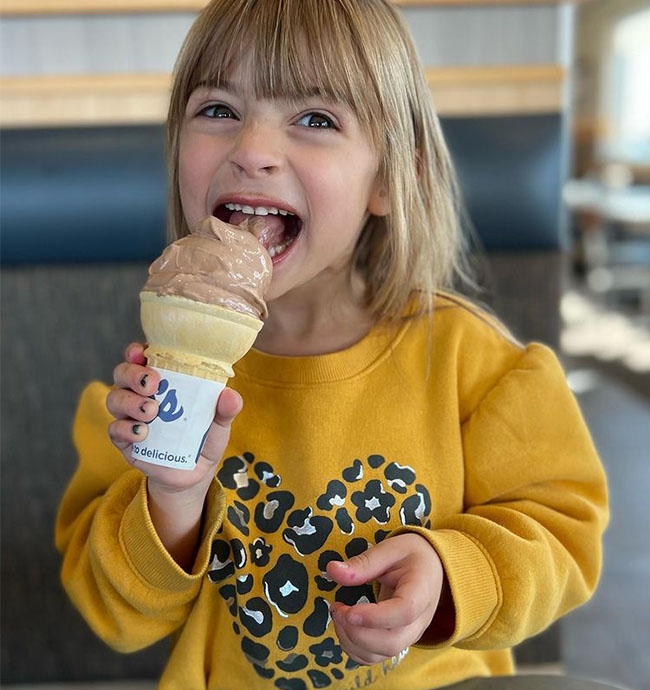 A young girl enjoys a cone of Chocolate Fresh Frozen Custard.