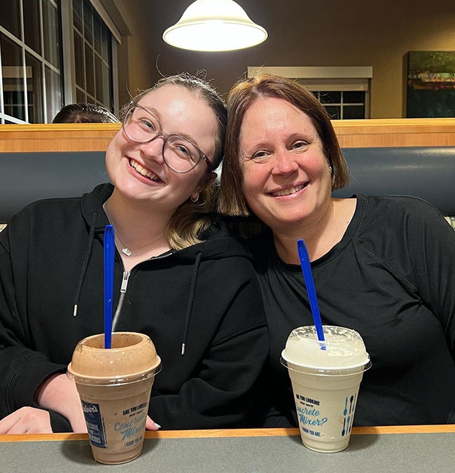 Two women smile in a Culver’s booth with Fresh Frozen Custard.
