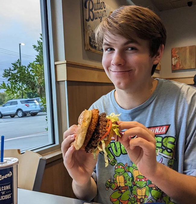 Man smiles as he holds a CurderBurger. 