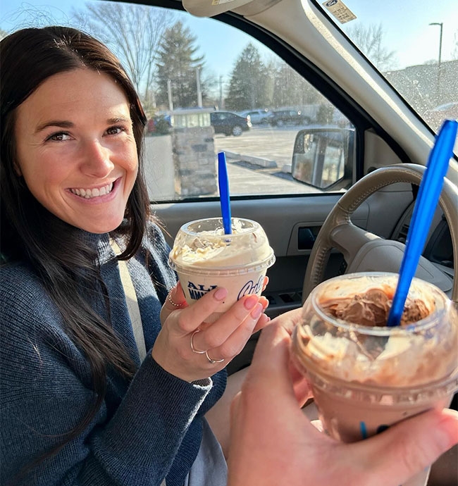 Woman smiles and holds a dish of Fresh Frozen Custard in a car.