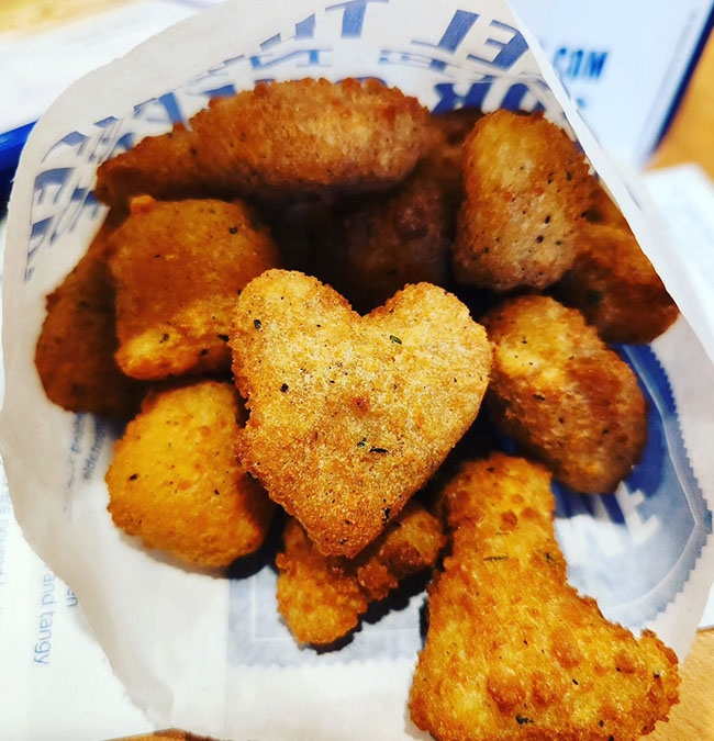 A heart-shaped Cheese Curd on a pile of other Cheese Curds. 