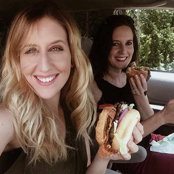 Two women eating Culver’s ButterBurgers® in their car, smiling at the camera
