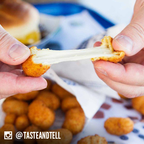 Culver’s guest pulling apart a Wisconsin Cheese Curd to see how far they can pull it before it breaks into two pieces.