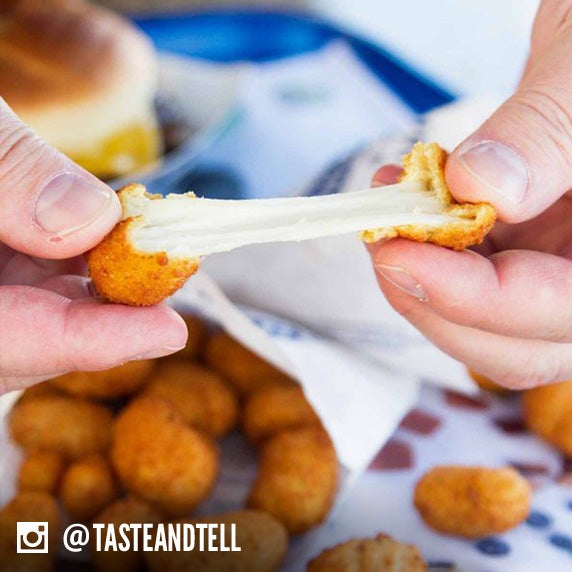 Culver’s guest pulling apart a Wisconsin Cheese Curd to see how far they can pull it before it breaks into two pieces.