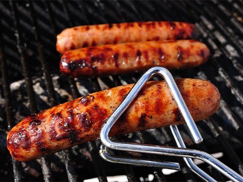 Brats cooking on a grill