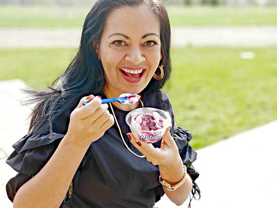 Smiling woman holds up a dish of Culver’s Blackberry Cobbler Fresh Frozen Custard.