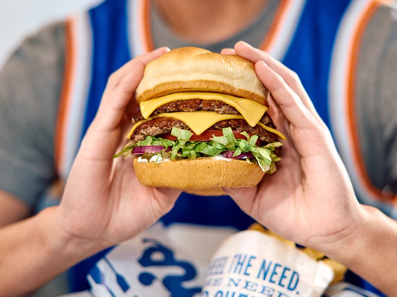 A customer holds a butterbuger with both hands towards the camera