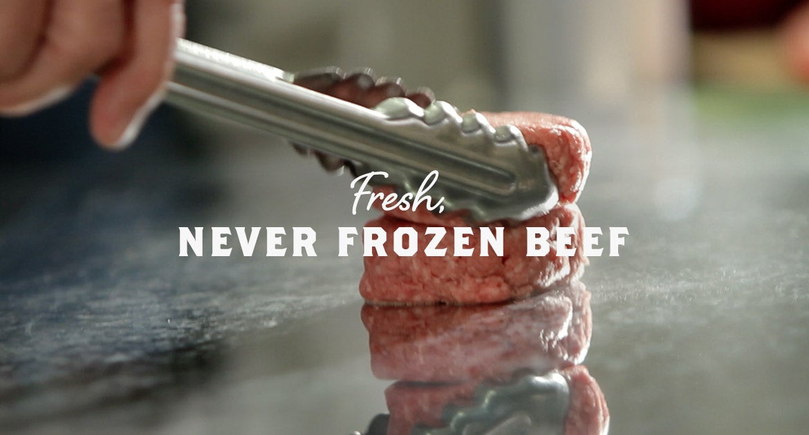 A beef patty on the grill with "Fresh Never Frozen Beef"