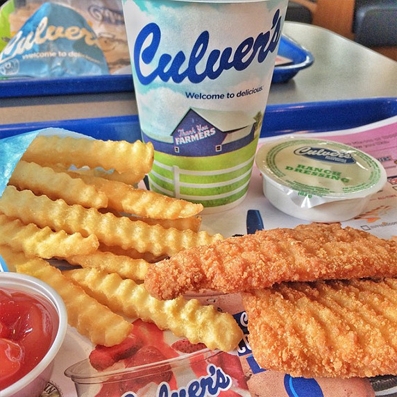 Two chicken tenders sitting next to crinkle cut fries, ranch dressing and a drink on a table in Culver’s restaurant 