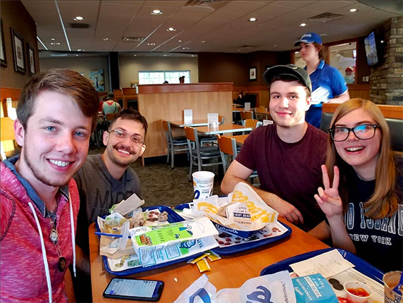 Four friends sit around a table at Culver’s, smiling for the camera.