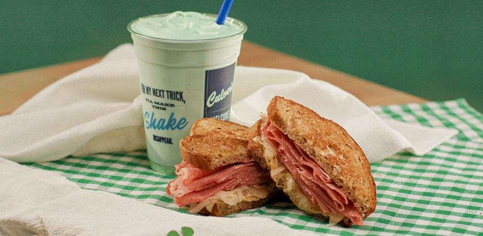 A Mint Shake and Grilled Reuben Melt rest on a green gingham tablecloth. 