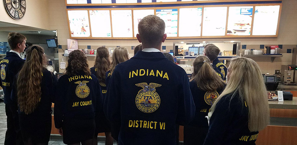 Photo of FFA members in their blue jackets stand in a Culver’s restaurant looking at the menu board.