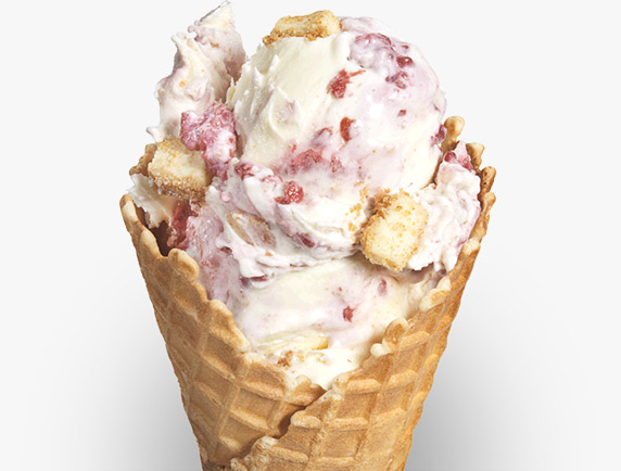 Small chunks of vanilla cheesecake and red raspberry pieces are mixed into vanilla frozen custard and served in a sugar cone