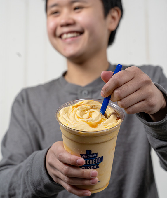 Person smiles and holds up Concrete Mixer with spoon.