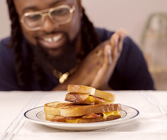 Man stares at plated Grilled Cheese with bacon.