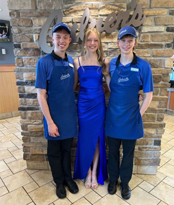 The brothers smile in their Culver’s uniforms next to their sister who is going to a school dance in a Culver’s blue dress.