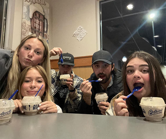Group of friends pose with scoops of custard.