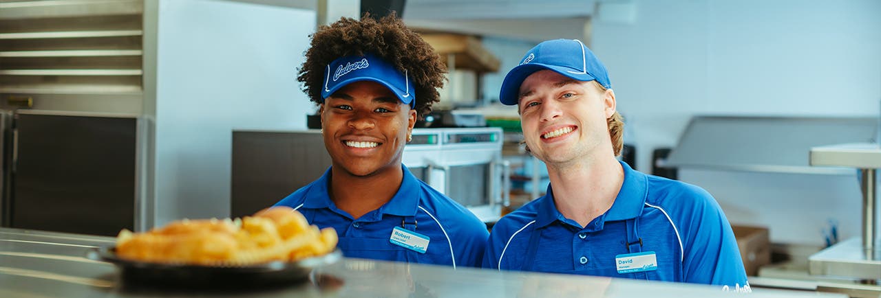 two culvers employees stand behind the kitchen window