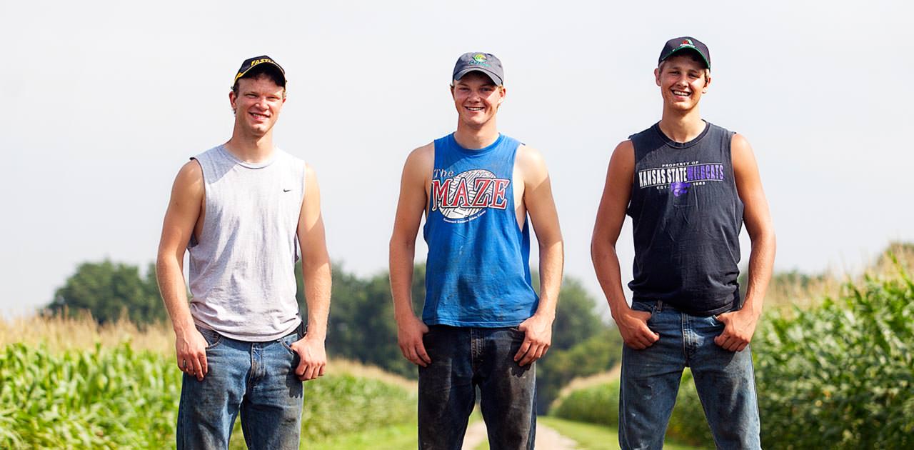 Peterson Farm Bros pose on a road between two cornfields