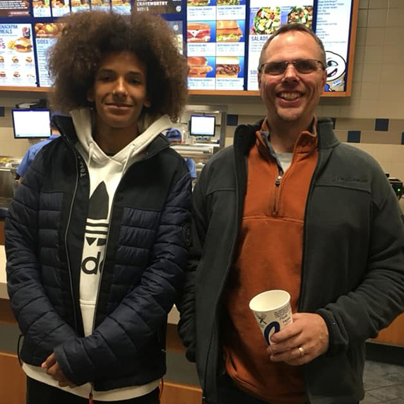 Tarik and Chad stand in front of the Culver’s menu.