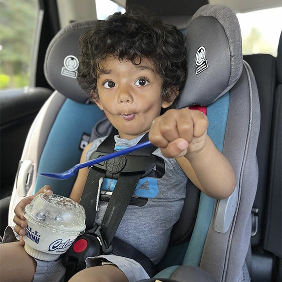 Little boy in a carseat eating custard