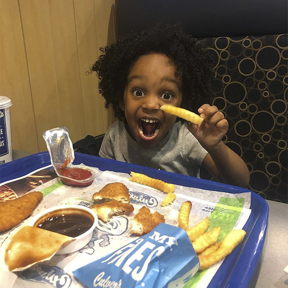 Little boy looking very excited and eating Culver'sfrench fries