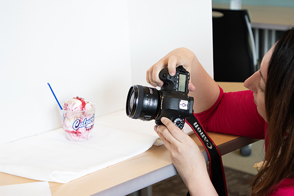 Woman holds camera up to photograph a dish of Culver’s Fresh Frozen Custard.