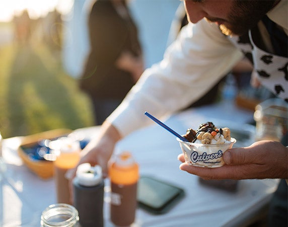 The groom, Cory, reaches for toppings to put on his dish of frozen custard.