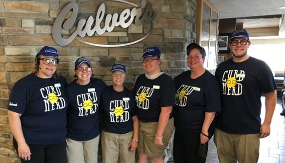 Sharon and team members pose in Culver’s Curd Nerd shirts.