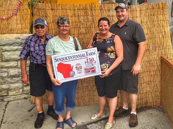 Randy, Marie and Randy’s parents pose with a sesquicentennial farm sign.