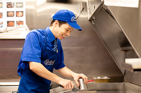 Robert presses and sears beef for a ButterBurger at a grill.