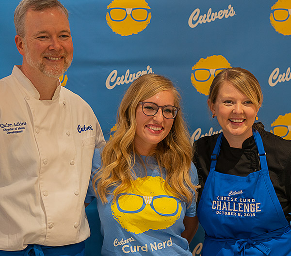 Quinn, Emily and a guest take photos with cheese curd props in front of a Culver’s backdrop