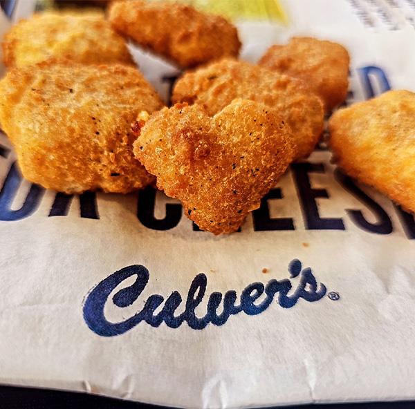 A Cheese Curd in the shape of a heart surrounded by other Cheese Curds.