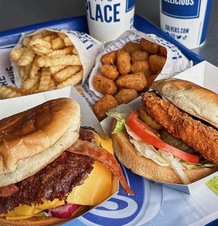 A Chicken Sandwich, ButterBurger, Cheese Curds and Crinkle Cut Fries on a table.