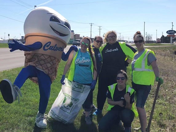 Team members stand on the side of the road after cleaning up trash and debris.