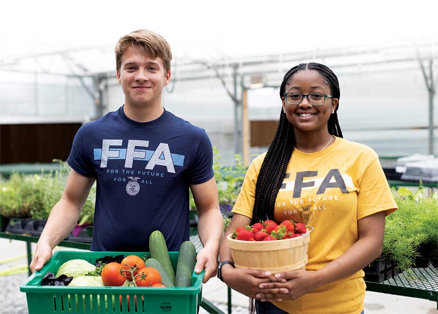 Two FFA members, each holding a basket of fresh produce