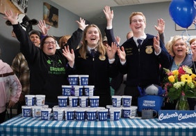 a group of people celebrate behind a table full of Culver's fresh frozen custard pints