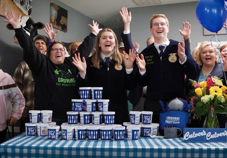 a group of people celebrate behind a table full of Culver's fresh frozen custard pints