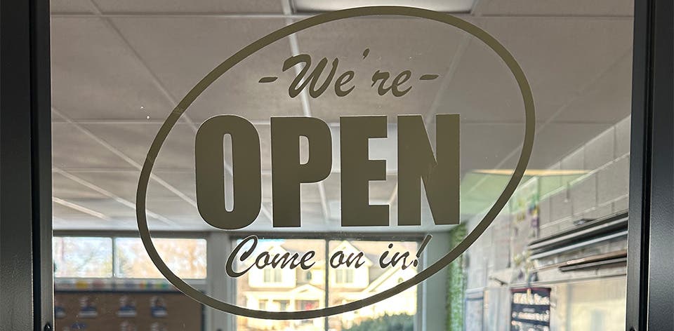 Classroom door with open sign and classroom hours