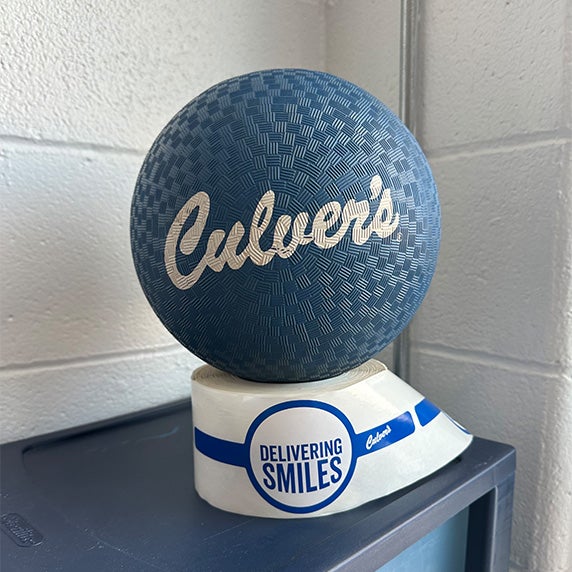 Culver&rsquo;s kickball on cabinet, propped on top of a roll of Culver's stickers.