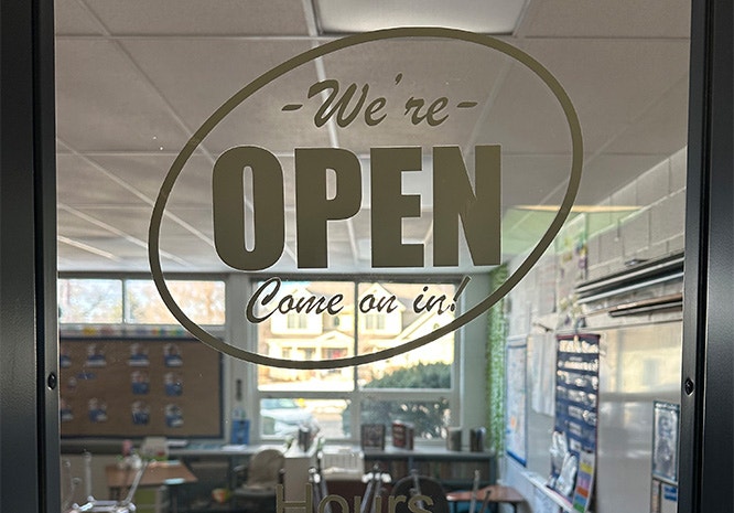 Classroom door with open sign and classroom hours
