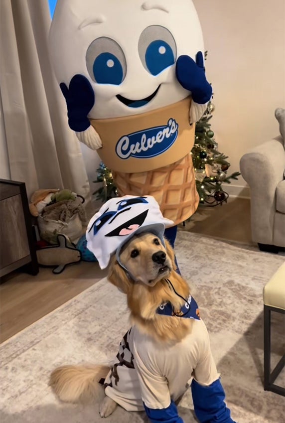 A dog in a Scoopie costume poses for a picture with Scoopie.