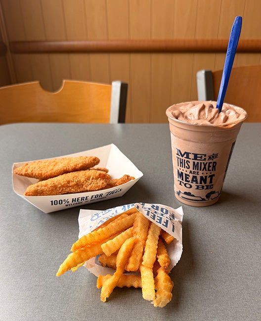 Chicken Tenders Value Basket sitting on table with Crinkle Cut Fries next to a Chocolate Concrete Mixer with cherries and cookie dough