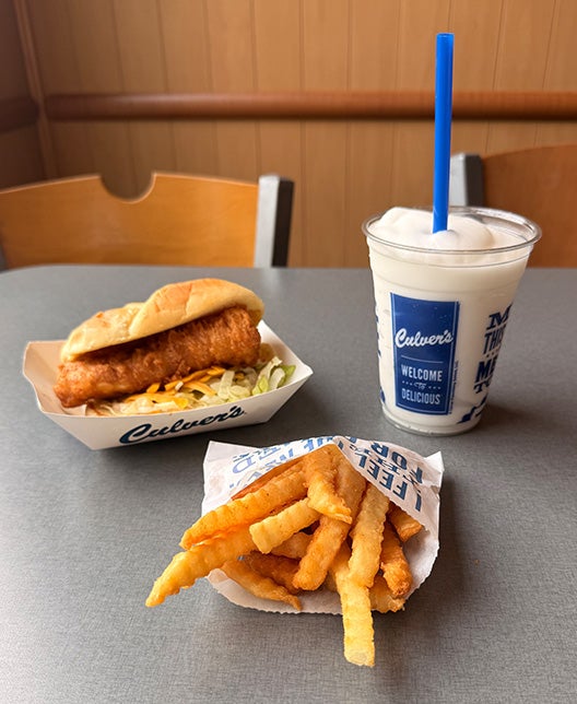 North Atlantic Cod Sandwich Value Basket sitting on table with Crinkle Cut Fries next to a Lemon Ice Cooler