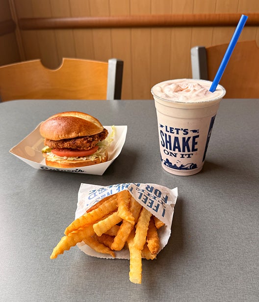 Spicy Chicken Sandwich Value Basket sitting on a table with Crinkle Cut Fries next to a Strawberry Shake