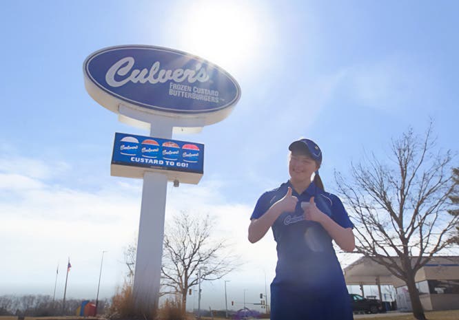 A True Blue Crew Member and Special Olympian Stands in Front of a Culver's Restaurant Sign