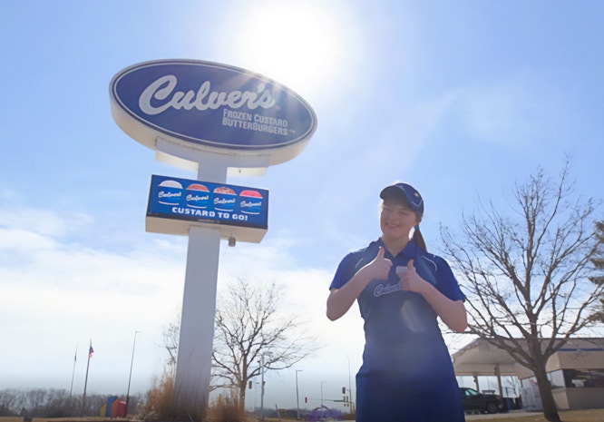 A True Blue Crew Member and Special Olympian Stands in Front of a Culver's Restaurant Sign