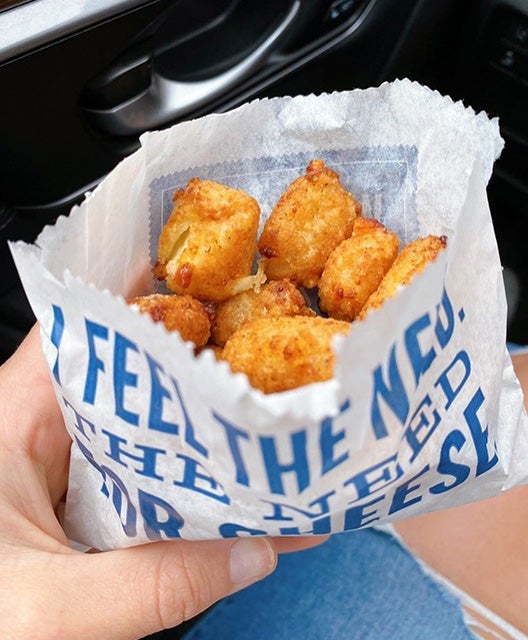 Hand holding a bag of Cheese Curds in a car