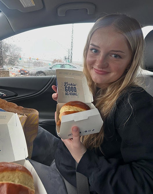 Woman holding a chicken sandwich in a car